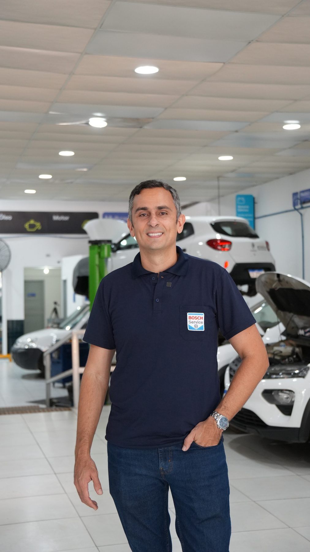 Responsável pela Multcar em pé dentro da oficina, de camisa polo Bosch Car Service